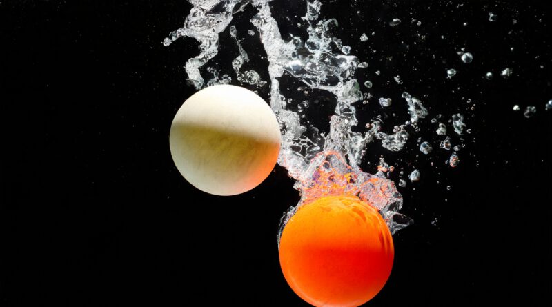 Generiert mit Adobe Firefly. two balls, ping pong; flying objects over water on black 64669.